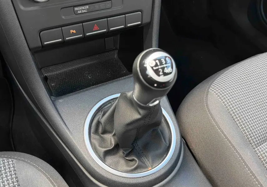 Gros plan sur le levier de vitesses manuel en cuir de la Volkswagen Coccinelle, entouré de la console centrale noire.