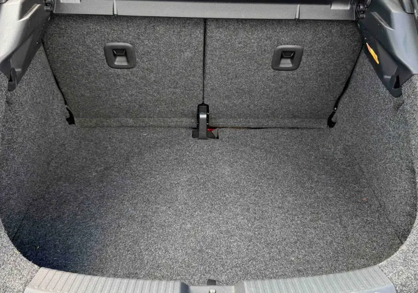 Coffre vide vu de face, revêtement gris, intérieur spacieux de la Volkswagen Coccinelle rouge 2012.