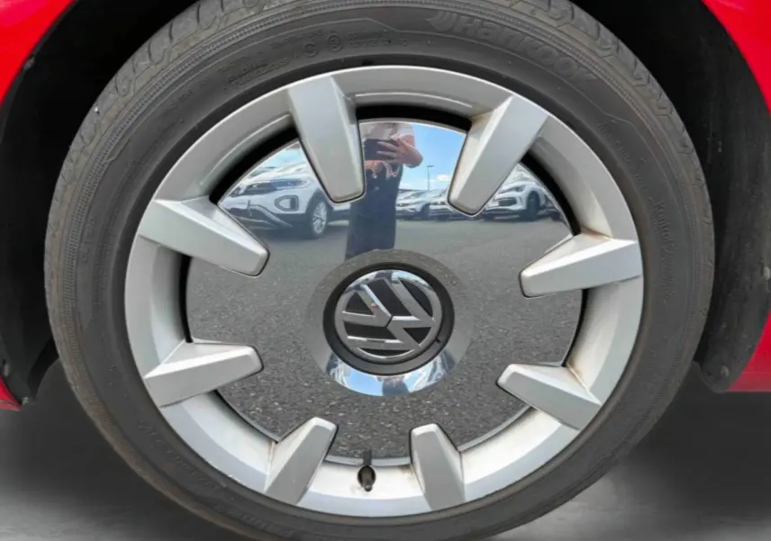 Gros plan sur la jante 18 pouces Disc argentée avec logo Volkswagen, entourée du pneu Hankook sur une Volkswagen Coccinelle rouge.