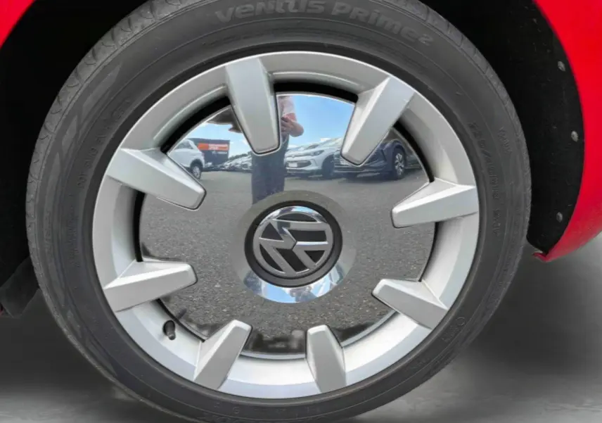 Gros plan sur la jante 18 pouces argentée avec logo Volkswagen, partie droite d'une Volkswagen Coccinelle rouge.