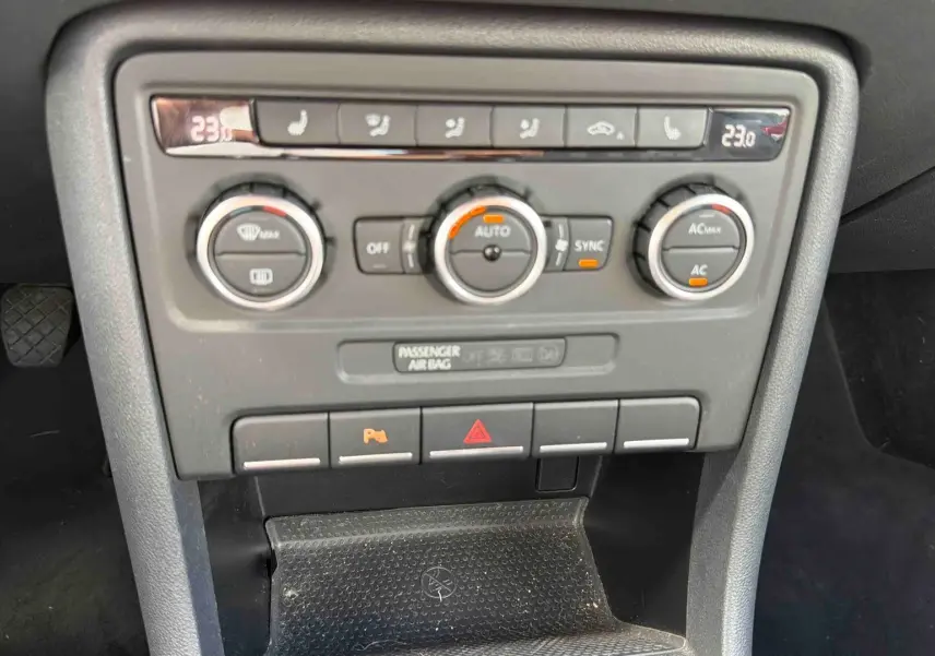 Vue rapprochée de la console centrale de la Volkswagen Coccinelle 2012, avec commandes de climatisation et boutons de fonction.