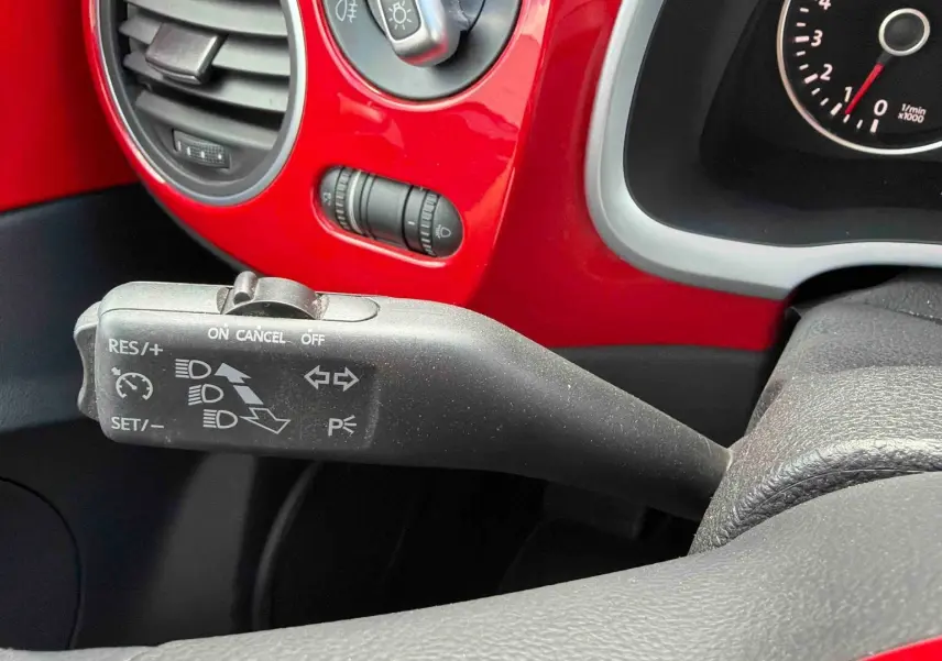 Gros plan sur le commodo de régulateur de vitesse dans l’habitacle rouge vif d’une Volkswagen Coccinelle 2012.