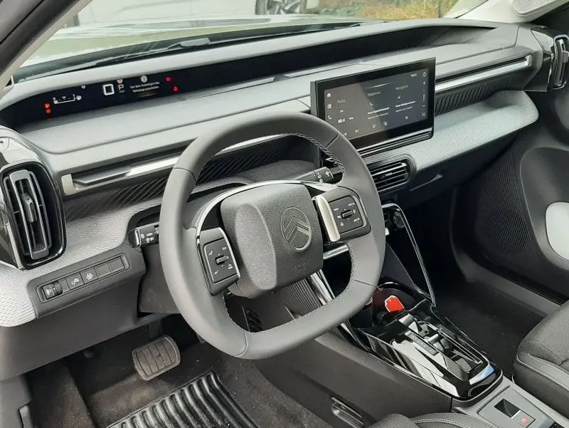 Vue intérieure côté conducteur du Citroën C3 Aircross hybride 2026, montrant le volant carré et l'écran tactile central.