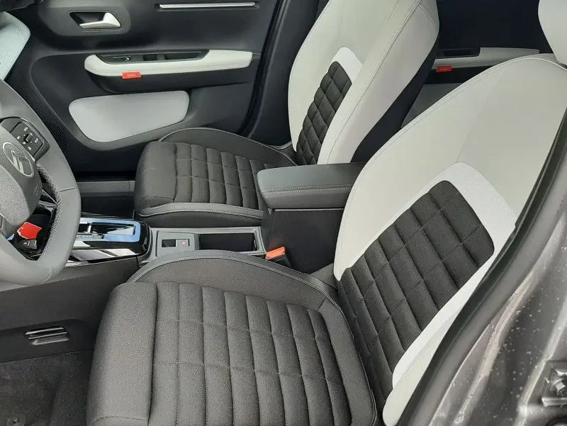 Vue intérieure côté conducteur de la Citroën C3 Aircross hybride 2026, sièges bicolores noir et beige, console centrale visible.