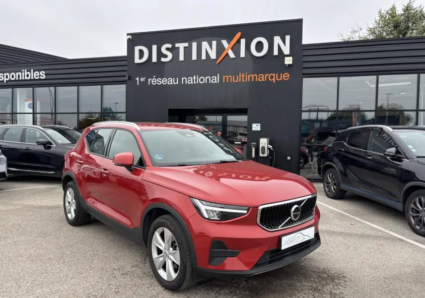 Volvo XC40 Fusion Red en 3/4 avant gauche, avec calandre distinctive et jantes alliage 18 pouces visibles.