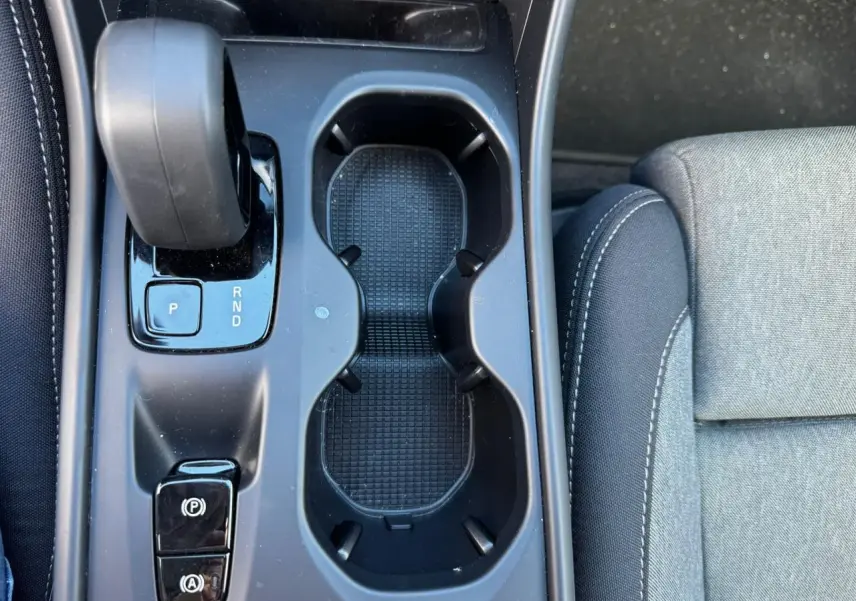 Vue plongeante sur la console centrale noire du Volvo XC40 avec levier de vitesses automatique et porte-gobelets.
