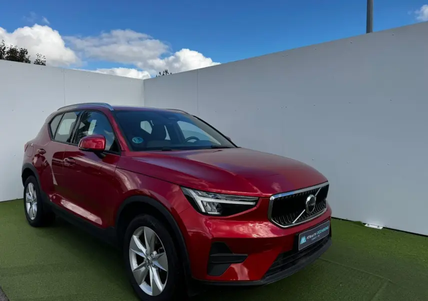 Volvo XC40 Fusion Red en 3/4 avant droit, avec jantes alliage 18 pouces et calandre noire distinctive.