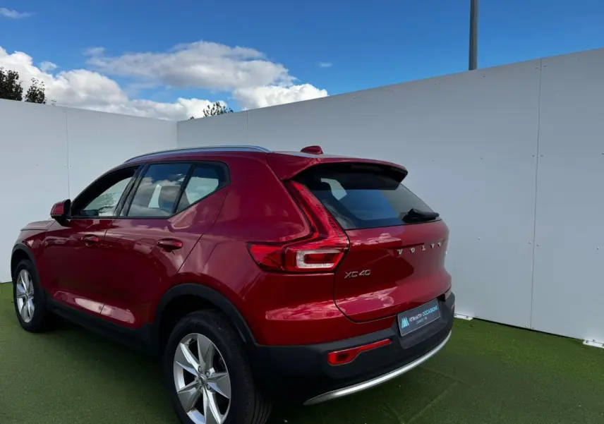 Vue 3/4 arrière droite d'un Volvo XC40 rouge Fusion Metal avec jantes alliage 18 pouces sur fond extérieur.