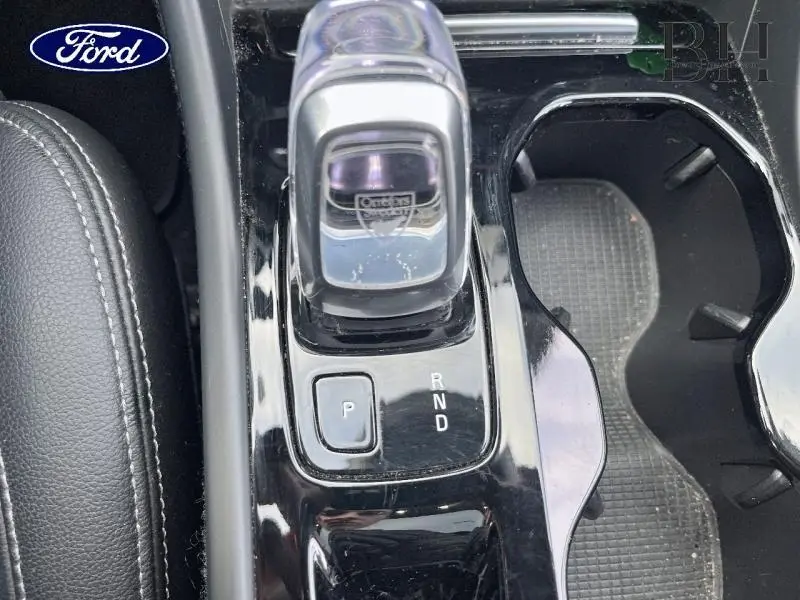 Le levier de vitesse automatique noir brillant d'un Volvo XC40 D3 Diesel vu de dessus avec porte-gobelets adjacent.