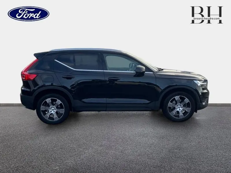 Profil côté droit d'un Volvo XC40 noir 2020 avec jantes alliage et vitres teintées sur fond neutre.