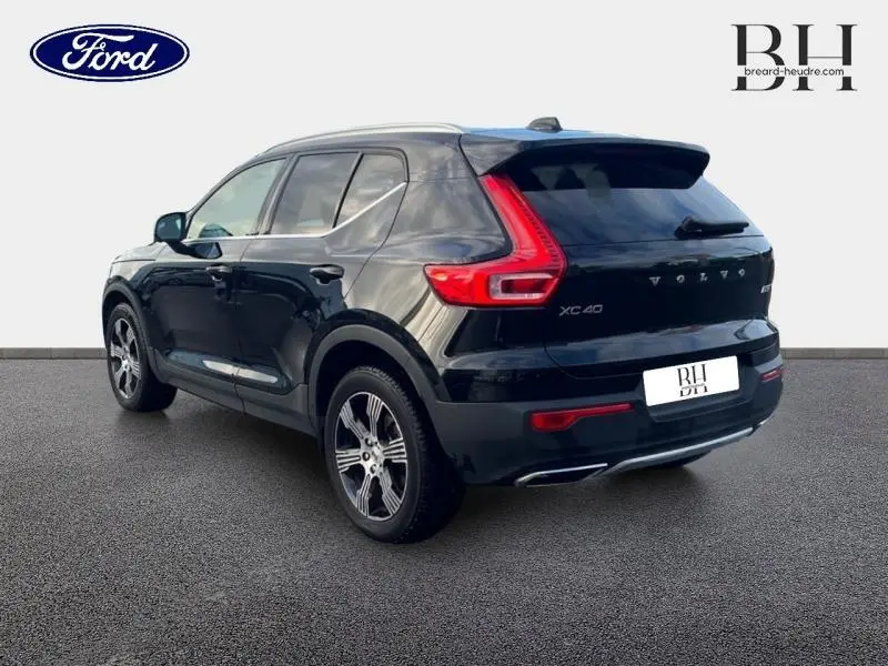 Volvo XC40 noir vue 3/4 arrière droit, soulignant ses feux arrière en L et ses jantes alliage modernes.