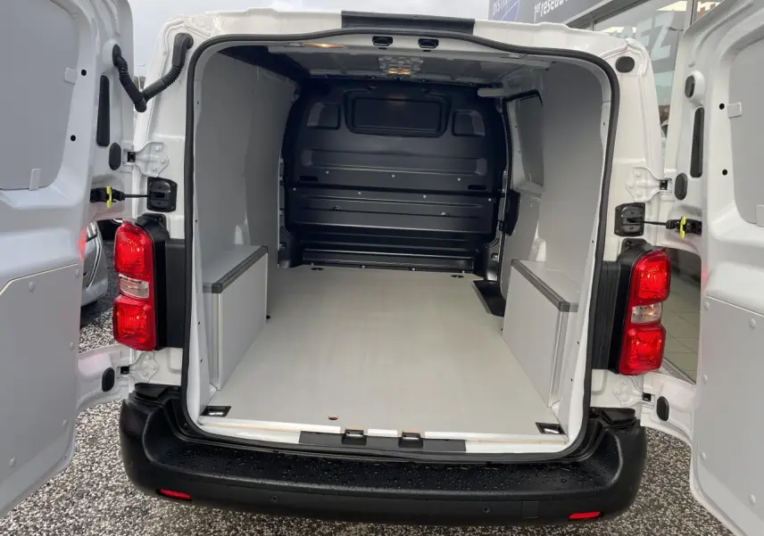 Vue arrière ouverte d’un Opel Vivaro blanc 2024 avec intérieur de chargement équipé de plancher et coffrages en bois.