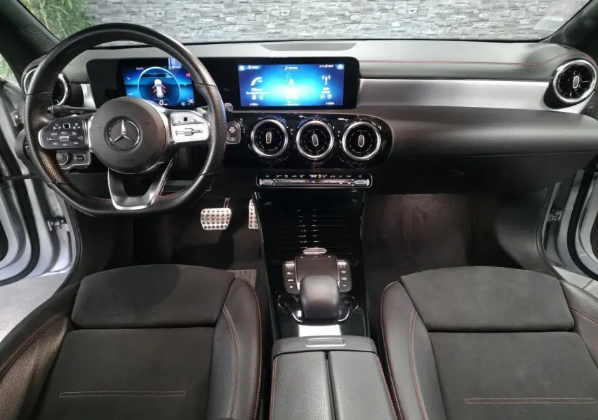 Vue intérieure avant de la Mercedes Classe CLA Shooting Brake 200 AMG Line 2020, tableau de bord noir avec écran digital et volant sport cuir.