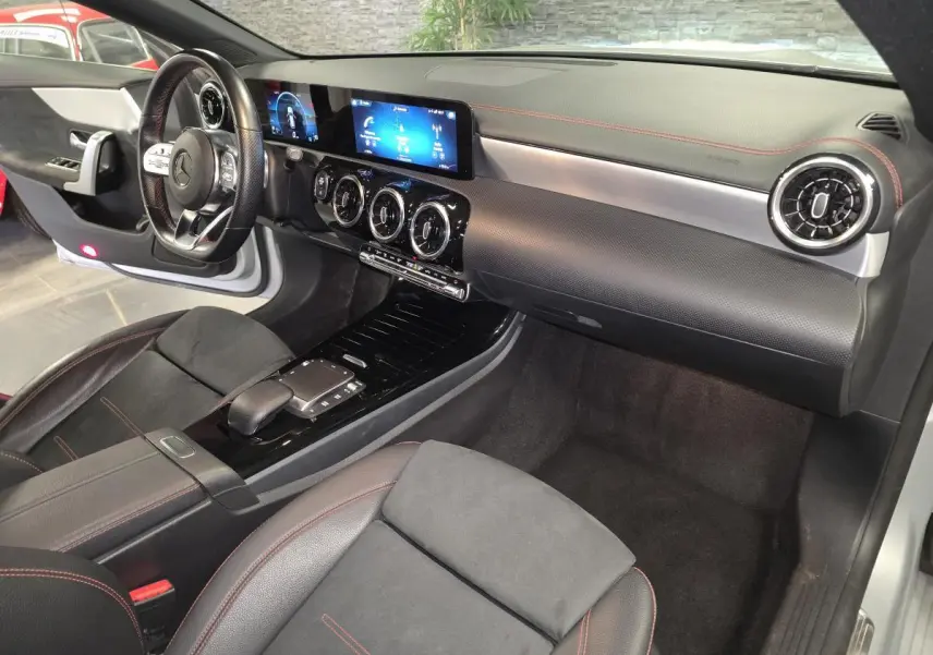 Vue intérieure côté passager de la Mercedes CLA Shooting Brake 200 AMG Line 2020 avec tableau de bord noir et surpiqûres rouges.