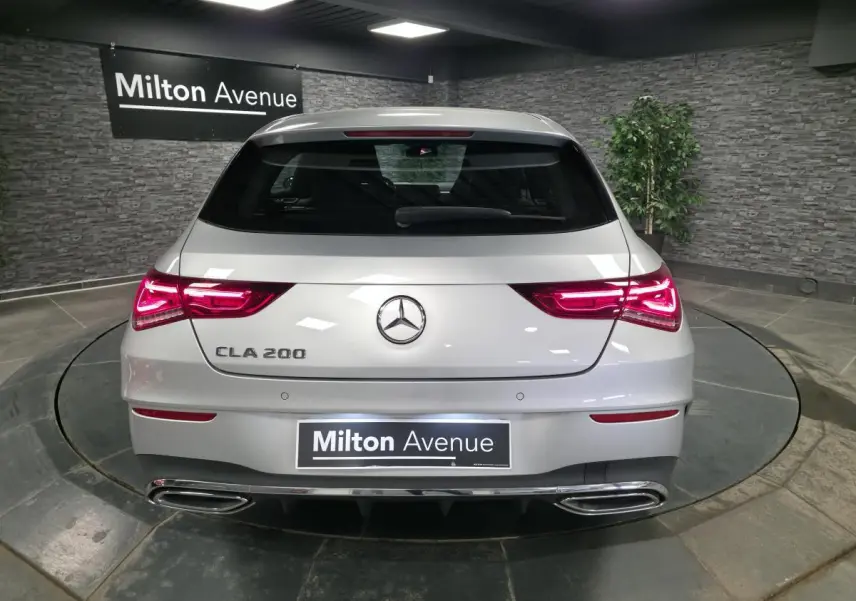 Vue arrière d'une Mercedes CLA 200 gris métallisé avec feux LED allumés et double sortie d'échappement chromée.