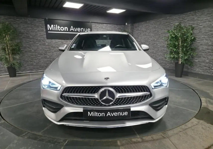 Mercedes Classe CLA Shooting Brake gris métallisé vue de face avec calandre diamant et phares LED allumés.