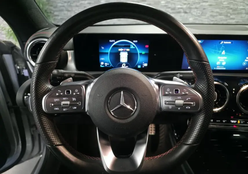 Vue rapprochée du volant sport noir avec surpiqûres rouges et tableau de bord digital de la Mercedes CLA Shooting Brake.