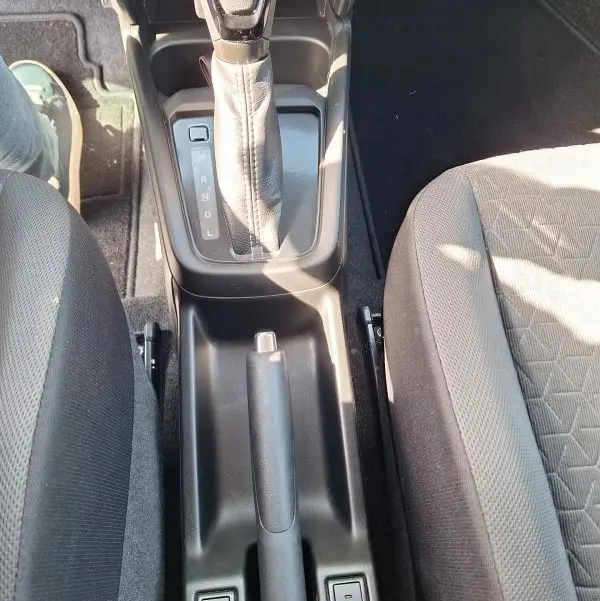 Vue plongeante sur la console centrale de la Suzuki Swift bleu 2025, avec levier de vitesse automatique et sièges tissu gris.