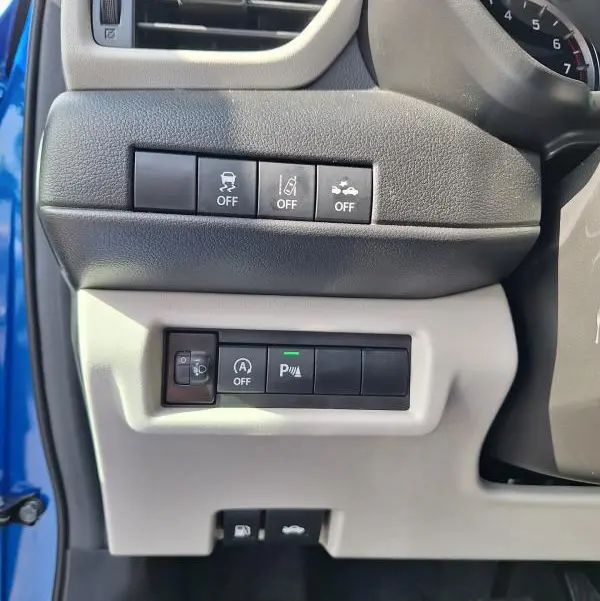 Vue intérieure côté gauche du tableau de bord bleu de la Suzuki Swift 2025, montrant les commandes d'aide à la conduite et ventilation.