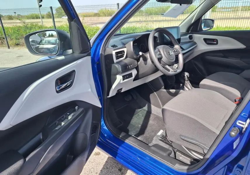 Intérieur côté conducteur d'une Suzuki Swift bleu 2025, montrant le volant, tableau de bord et sièges gris.