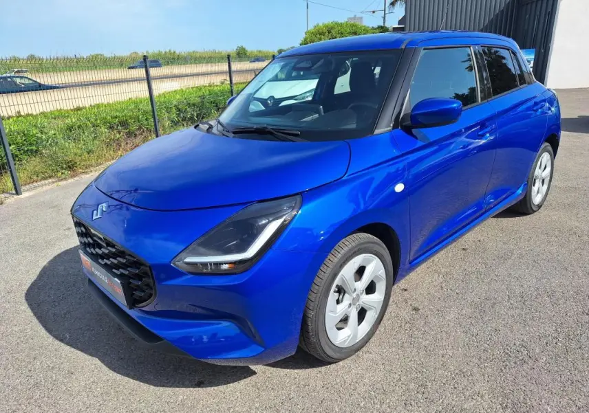 Suzuki Swift 1.2 Hybrid bleu en 3/4 avant droit, avec jantes alliage 16 pouces et feux LED distinctifs.