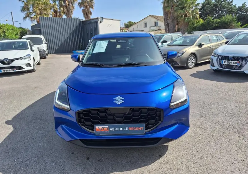 Vue avant d'une Suzuki Swift 1.2 Dualjet Hybrid Privilege bleu vif avec calandre noire et feux LED allumés.