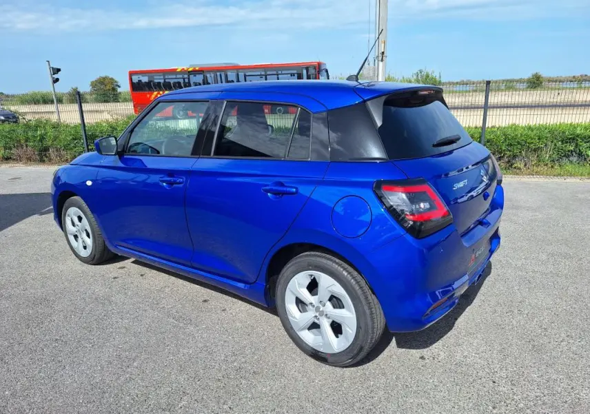 Suzuki Swift 2025 bleu en vue 3/4 arrière droit, avec jantes alliage 16 pouces et vitres teintées.