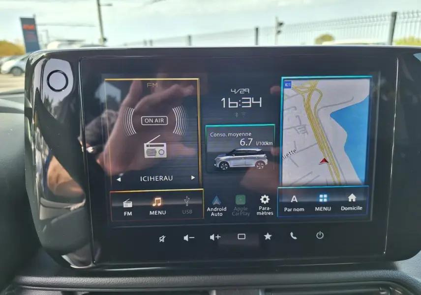 Écran tactile central de la Suzuki Swift 2025 affichant navigation, consommation et radio, intérieur noir.