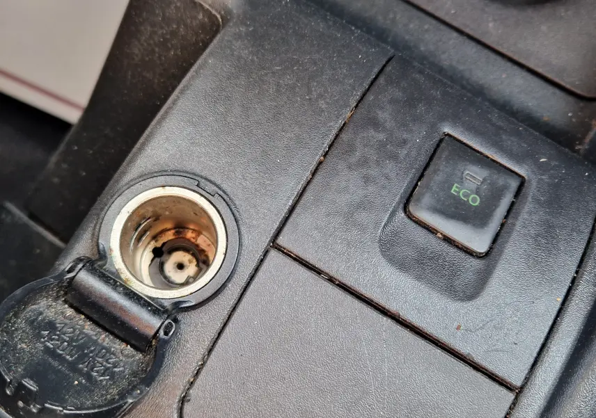 Gros plan sur la console centrale noire du Renault Kangoo blanc, montrant la prise 12V ouverte et le bouton ECO.