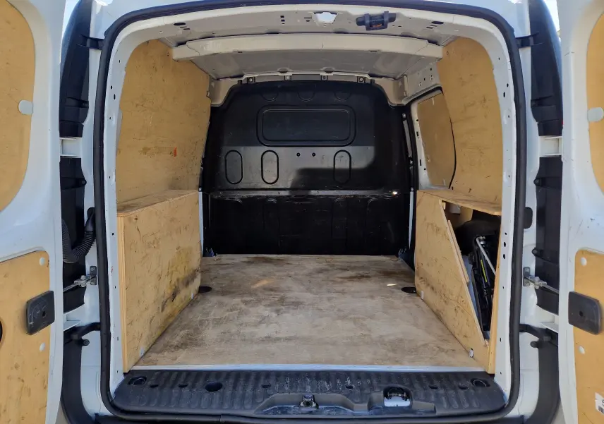 Vue arrière ouverte du Renault Kangoo blanc 2021, montrant l'espace de chargement avec aménagements en bois sur les côtés.