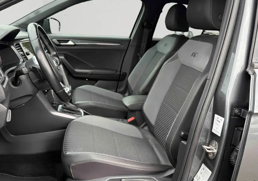 Vue intérieure côté conducteur du Volkswagen T-Roc gris Indium, sièges R-Line en similicuir avec surpiqûres grises.