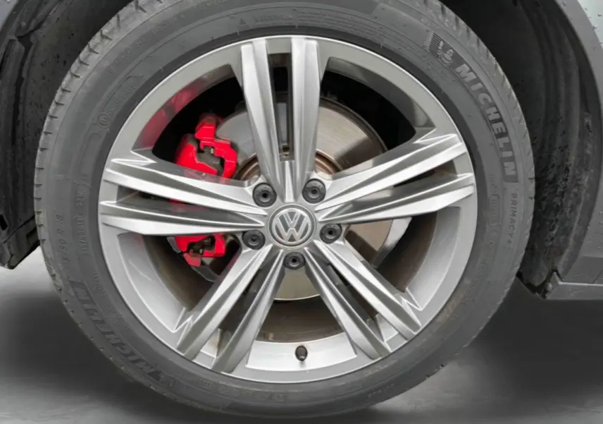 Gros plan sur la jante alliage 18 pouces Nevada gris argent avec étrier de frein rouge du Volkswagen T-Roc gris Indium Metal.