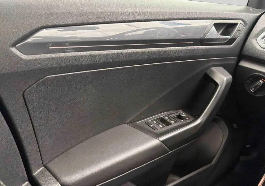 Vue rapprochée de la porte avant gauche du Volkswagen T-Roc 2020, avec accoudoir en similicuir et commandes électriques.