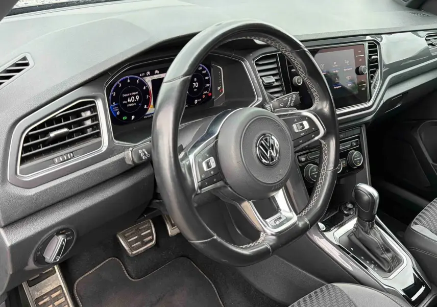 Vue intérieure centrée sur le volant cuir multifonctions et le tableau de bord digital du Volkswagen T-Roc gris Indium.