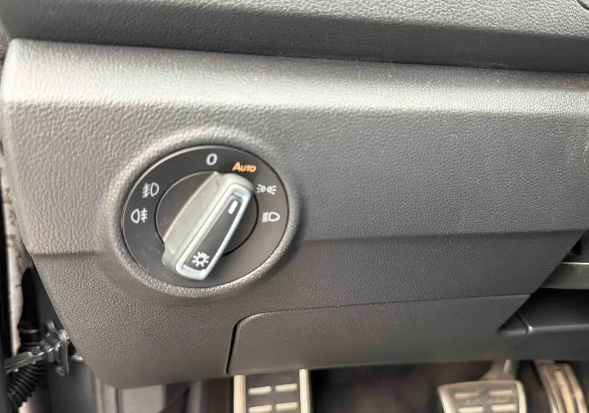 Gros plan sur la commande des feux à gauche du volant dans l’habitacle du Volkswagen T-Roc gris Indium.