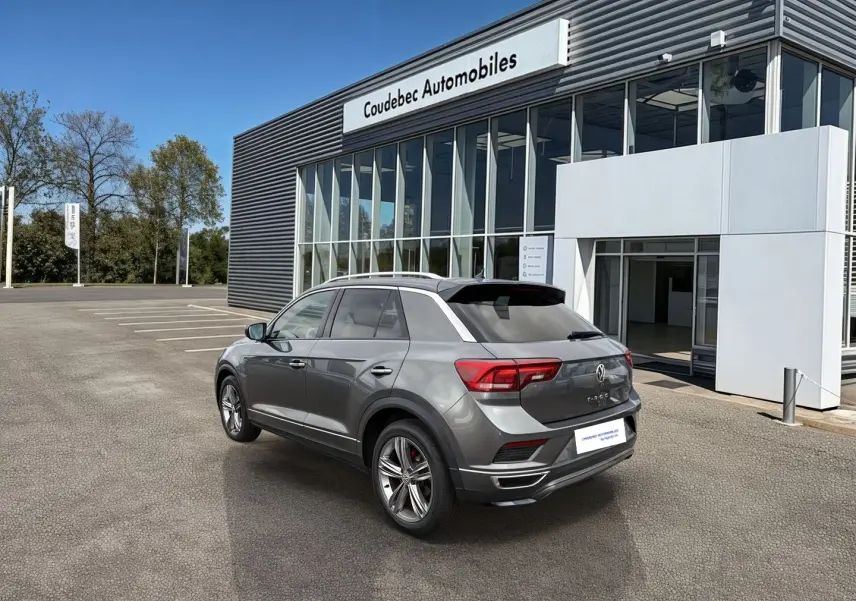 Volkswagen T-Roc gris Indium métal en 3/4 arrière droit, avec jantes alliage et feux LED, devant concession.
