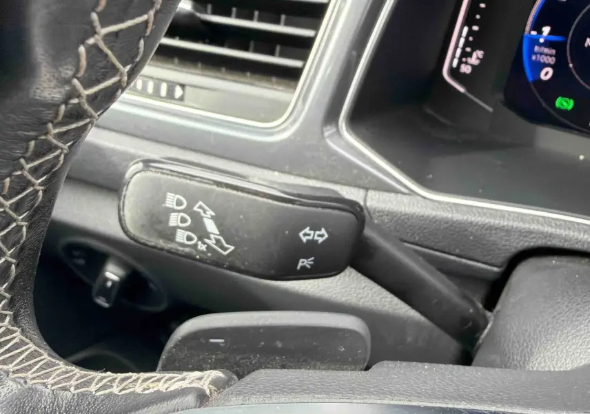 Gros plan sur le volant cuir et la commande de clignotants du Volkswagen T-Roc 2020, intérieur noir.