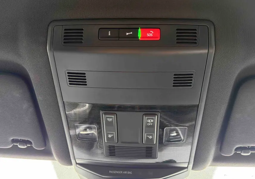 Vue intérieure du plafonnier du Volkswagen T-Roc gris Indium, avec commandes d’éclairage et bouton SOS rouge.