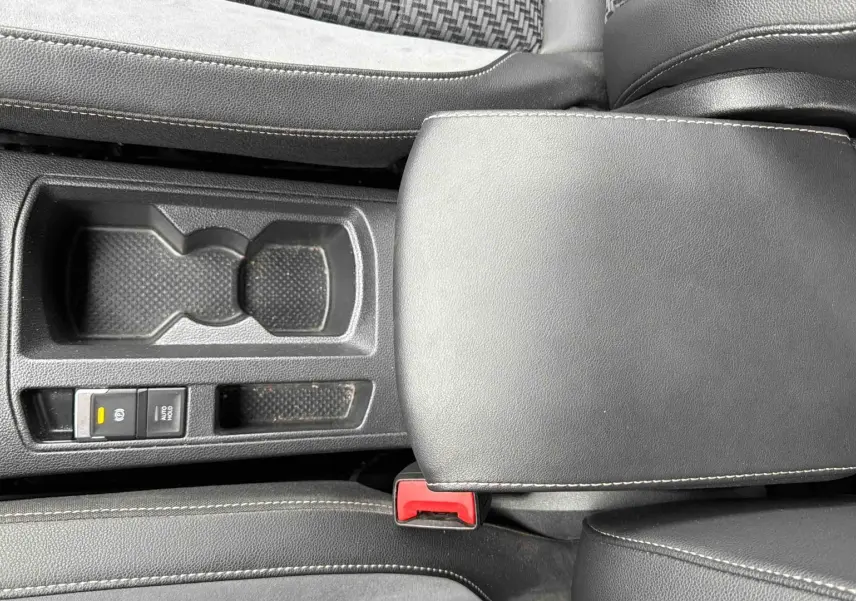 Vue plongeante sur l'accoudoir central en similicuir noir et la console centrale du Volkswagen T-Roc gris Indium.