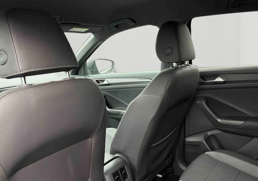 Vue intérieure arrière du Volkswagen T-Roc 2020 avec sièges en similicuir noir et détails modernes sur les portières.