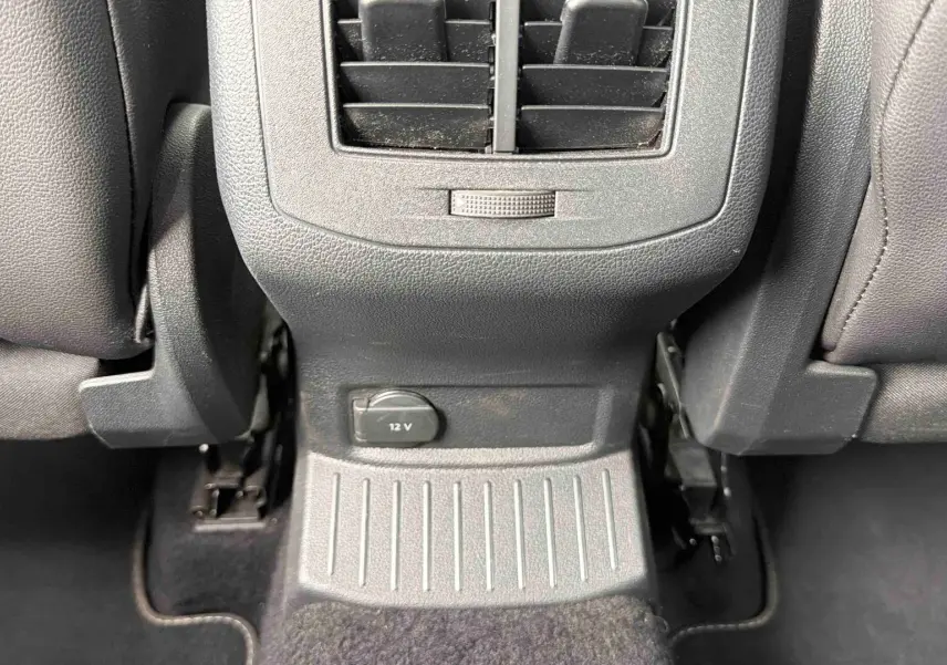 Détail de la console arrière grise avec prise 12V et aérateur entre les sièges arrière du Volkswagen T-Roc gris Indium.