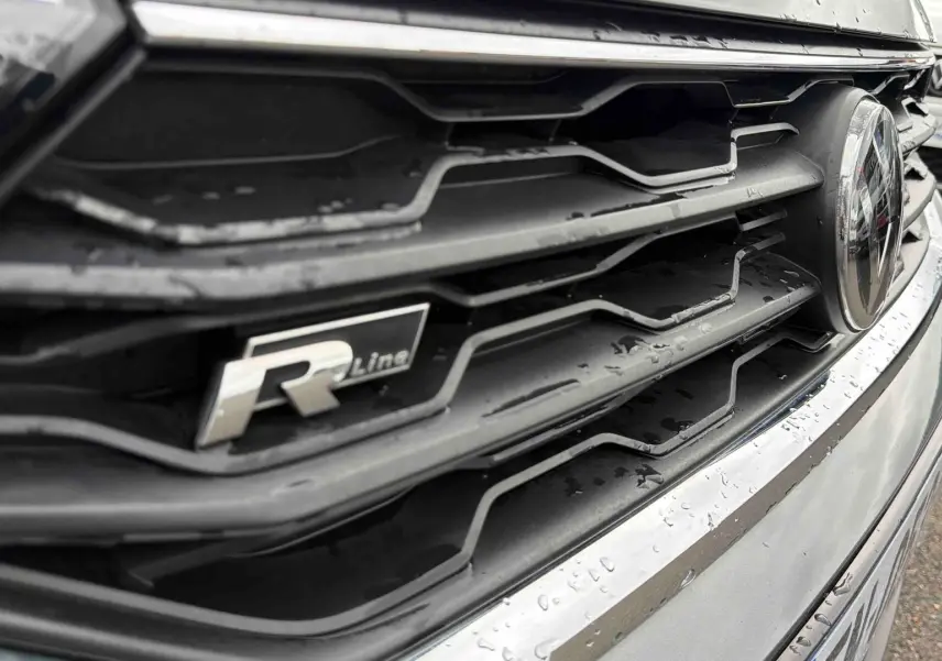 Gros plan sur la calandre avant grise indium métallisée du Volkswagen T-Roc 2020 avec logo R-Line et badge VW.
