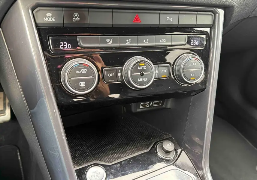 Vue rapprochée de la console centrale noire brillante du Volkswagen T-Roc 2020 avec commandes de climatisation et ports USB.