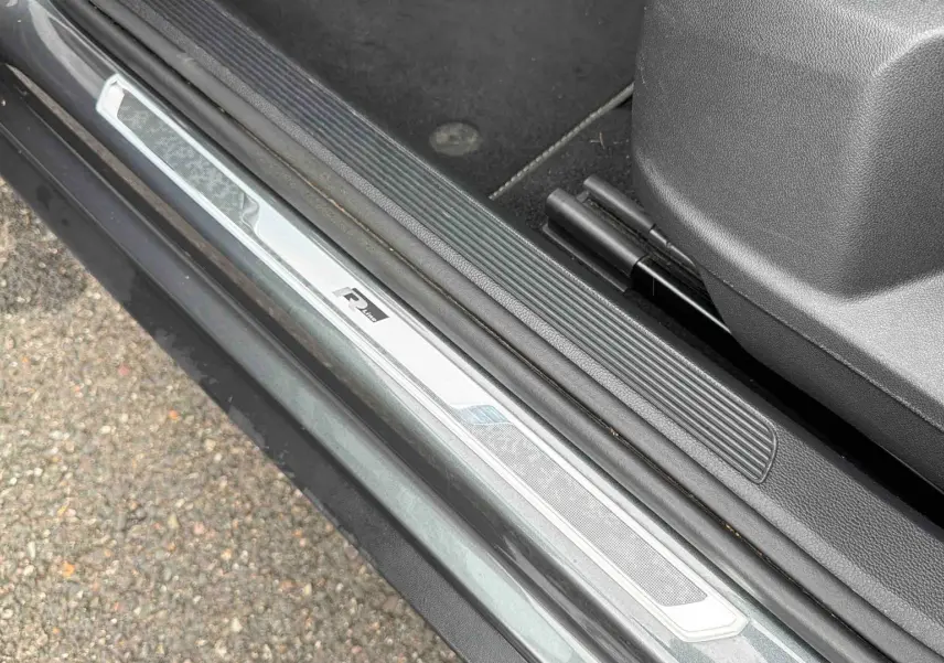 Gros plan sur la plaque de seuil de porte côté gauche du Volkswagen T-Roc gris Indium avec logo R-Line.