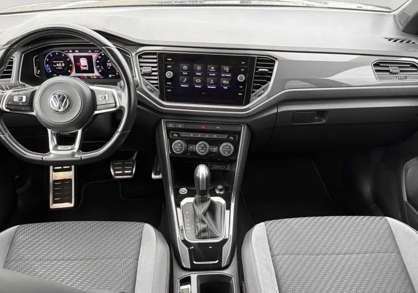Vue intérieure frontale du tableau de bord et console centrale noire du Volkswagen T-Roc 2020 avec volant cuir multifonctions.