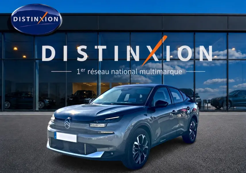 Citroën C4 X gris mercure en 3/4 avant droit devant une vitrine avec logo Distinxion.