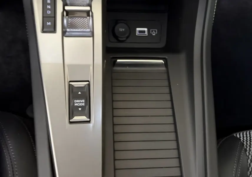 Vue plongeante sur la console centrale noire et grise du Peugeot 308 Hybrid 2025 avec bouton start et commande boîte auto.