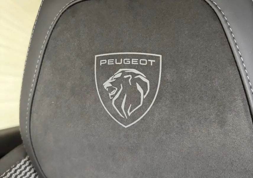 Gros plan sur l'appui-tête noir avec logo Peugeot gravé, sur un siège tissu et cuir de la Peugeot 308 GT.