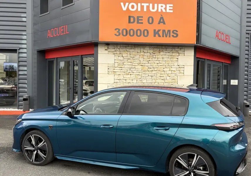 Vue latérale gauche d'une Peugeot 308 1.2 Hybrid 145 GT bleu métallisé, avec jantes alliage et toit panoramique.