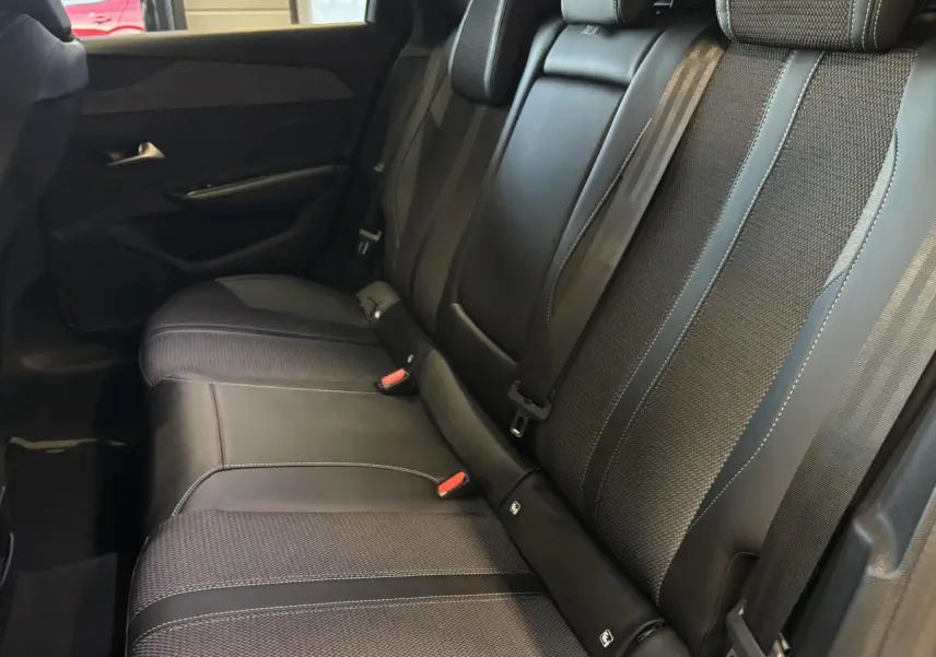 Vue latérale intérieure montrant la banquette arrière en sellerie tri matières noire avec surpiqûres bleues du Peugeot 308 SW 2024.
